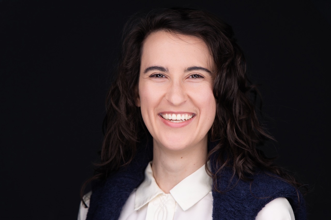 Executive headshot in Denver of a woman with curly hair in a navy vest by Rocky Mountain Photography